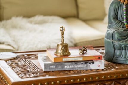 Close-up of a decorative bell and books on a carved wooden table in a cozy setting.